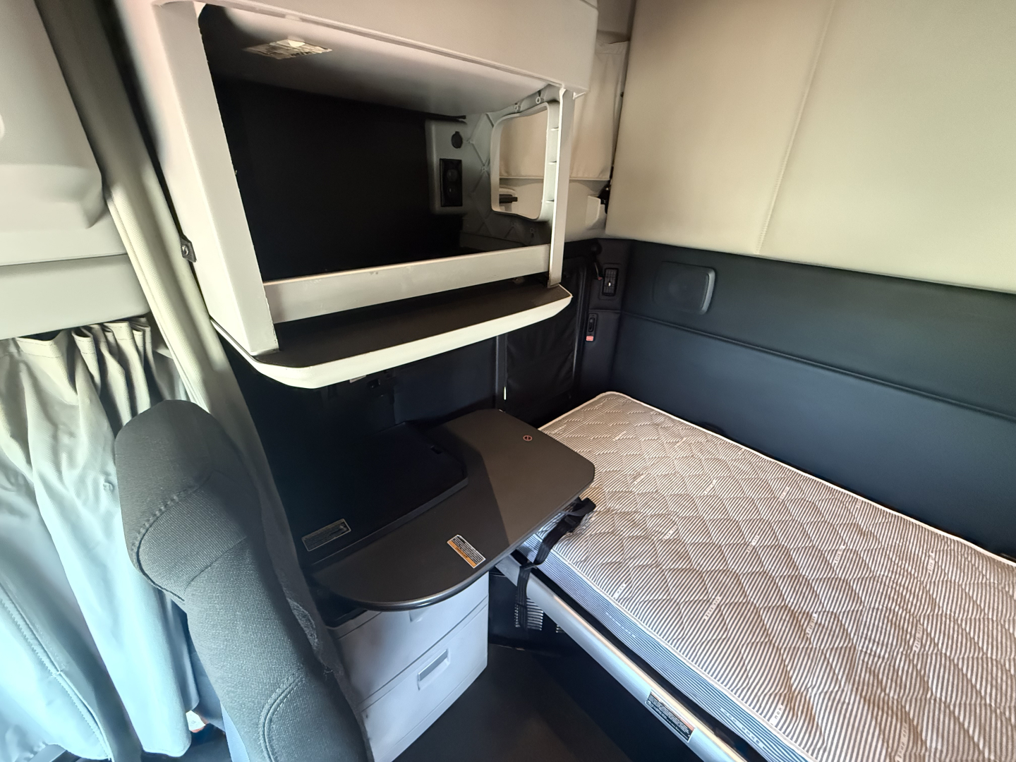 Kenworth T680 sleeper cab interior showing bunk area and desk/locker during cab inspection.