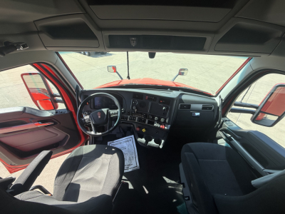 Kenworth T680 cab interior showing driver seat and dashboard with steering wheel and control panel.