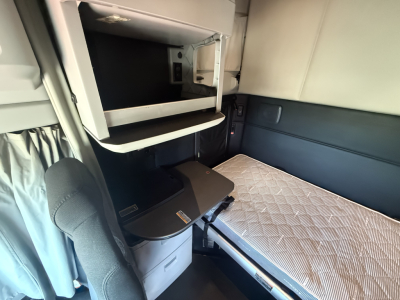 Kenworth T680 sleeper cab interior showing bunk area and desk/locker during cab inspection.