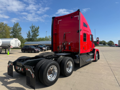 Kenworth T680 tractor in red cab, rear view showing axle assemblies and fifth wheel, no visible text on cab.