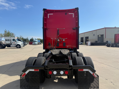 Kenworth T680 tractor tractor rear view showing red sleeper cab, dual rear axles, and rear chassis with mud flaps and lights.