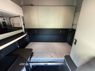Kenworth T680 sleeper cab interior. View of the bed with a mattress, side storage, and bunk area visible.