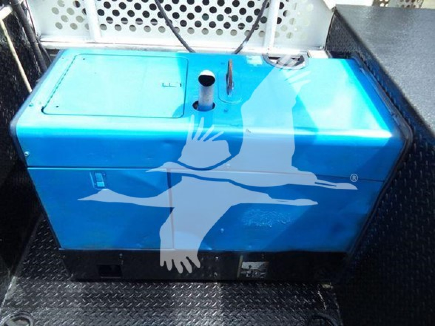 Blue fuel or water tank inside truck bed showing a white bird logo with a cross-like shape, cap and vents on top.