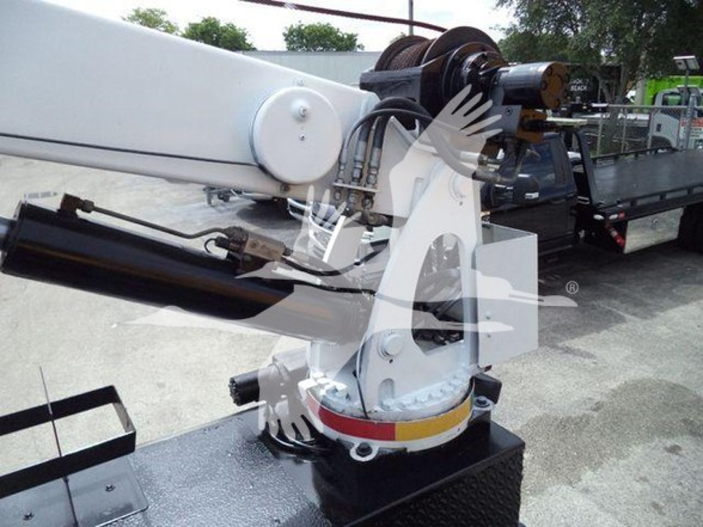 Hydraulic articulating crane on a Kenworth truck with white/yellow base and black hydraulic cylinder visible.
