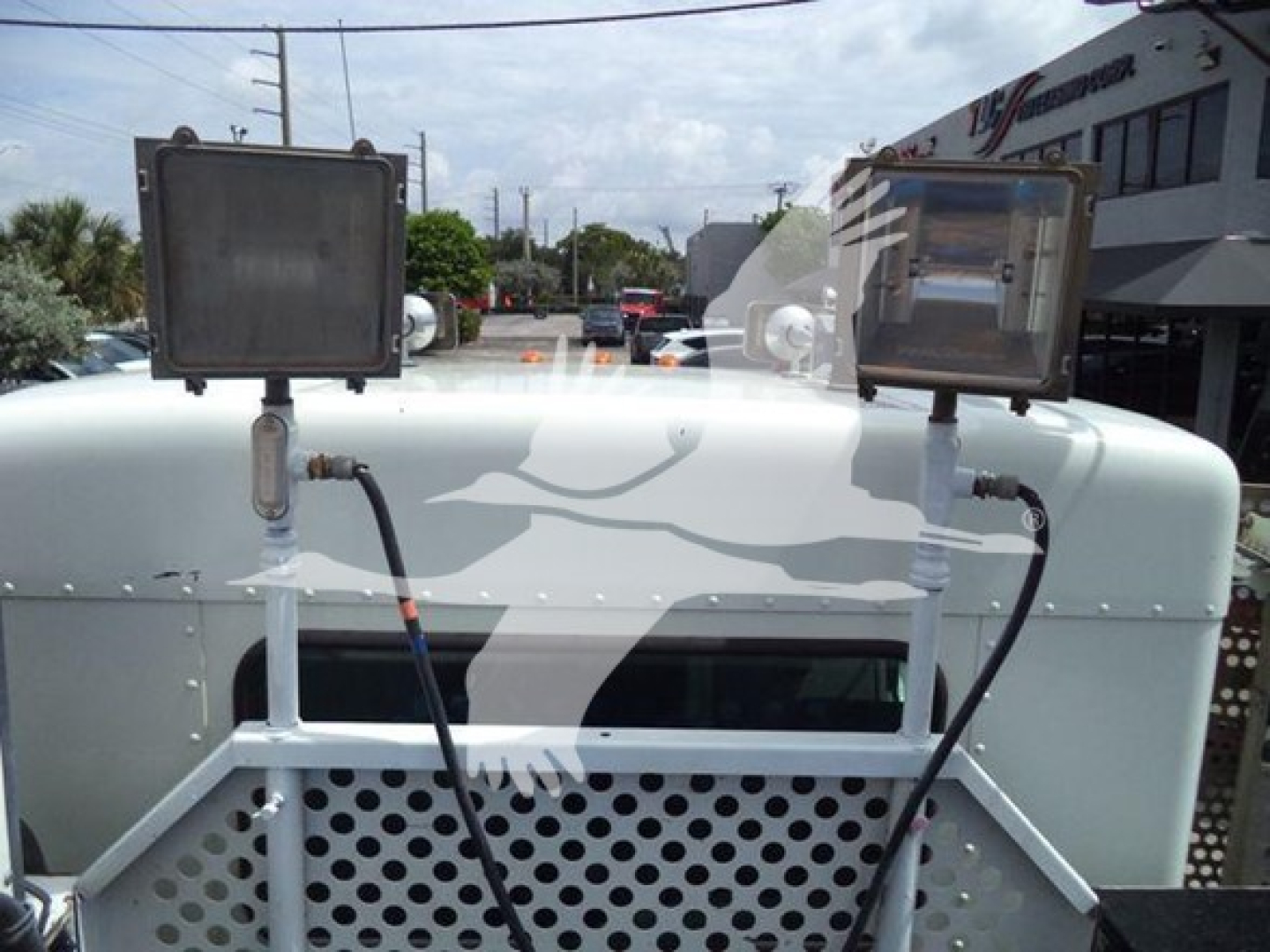 Kenworth T270 front view showing dual rectangular work lights mounted on a white grille with perforated metal; electrical wiring and brackets visible.
