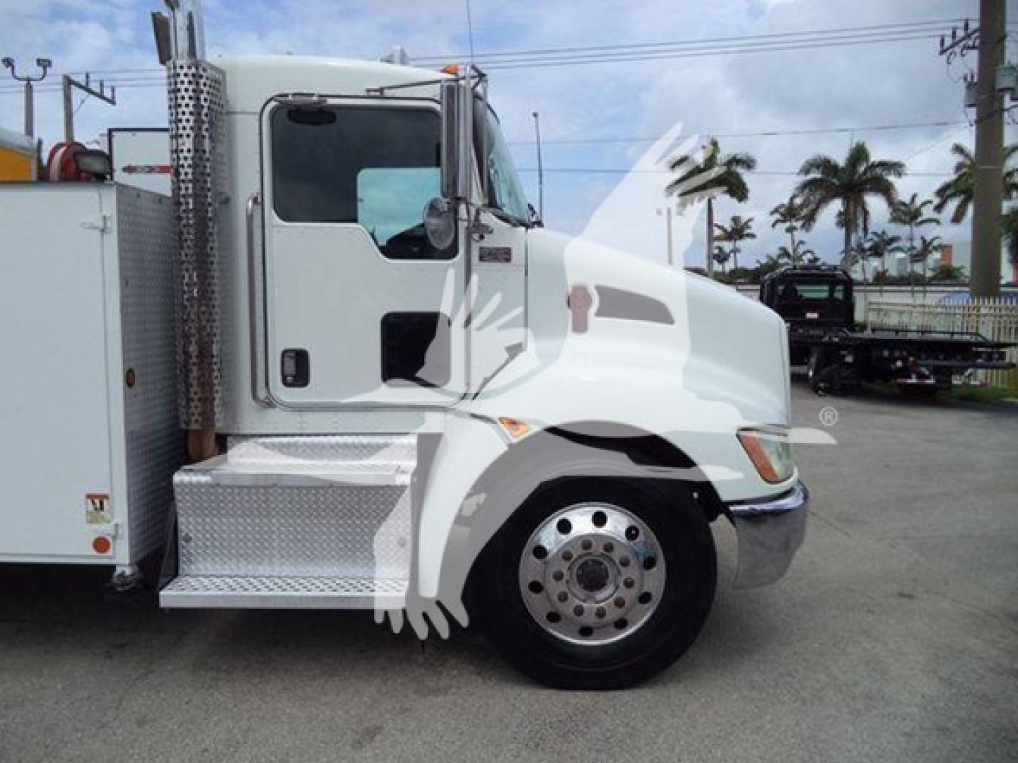 Kenworth T270 truck side view showing cab and front wheel, with a service box adjacent; operational dealership lot background.
