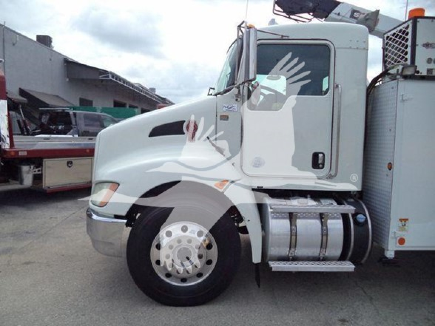 Truck cab of a white 2014 Kenworth T270 side view showing front wheel, fuel tanks, and passenger door.