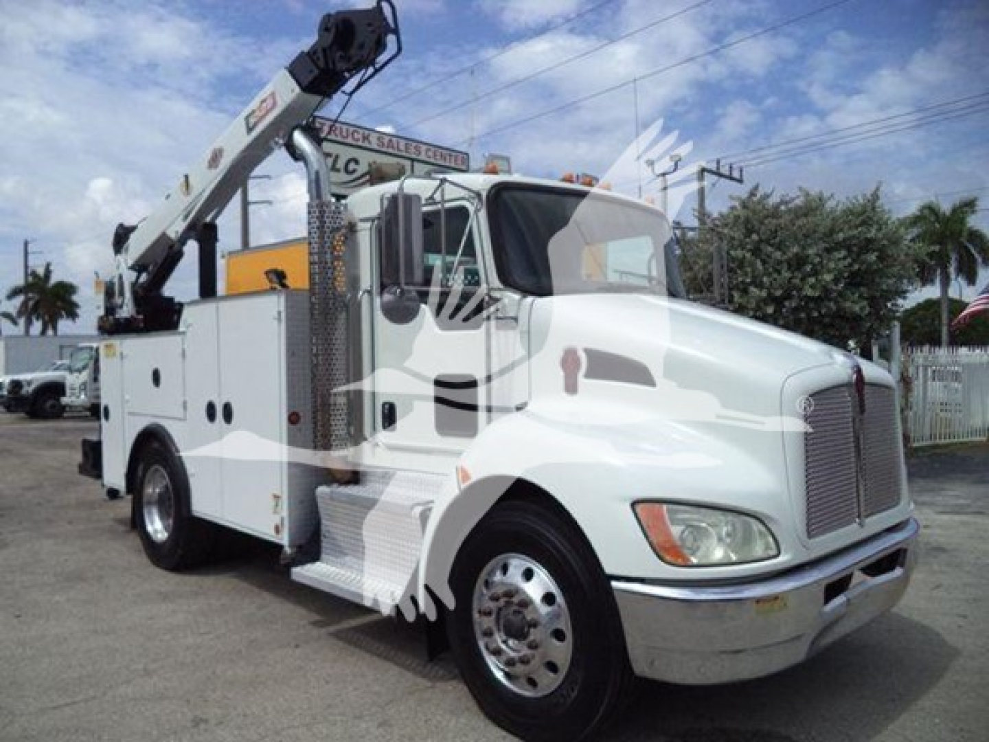 Kenworth T270 utility/service truck with boom lift, white cab and utility body, side steps, chrome wheels, and hydraulic crane arm visible.