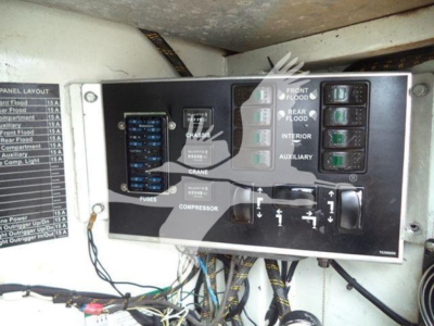 Kenworth T270 service truck engine bay control panel with labeled switches and fuse panel; visible text includes FUSES, COMPRESSOR, CRANE, FRONT FLOOD, REAR FLOOD, INTERIOR, AUXILIARY, and a layout diagram; small label on left lists panel l