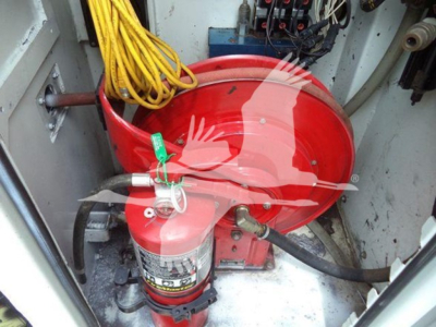Kenworth truck interior showing a red fire suppression bottle and yellow hoses in the cabinet side.