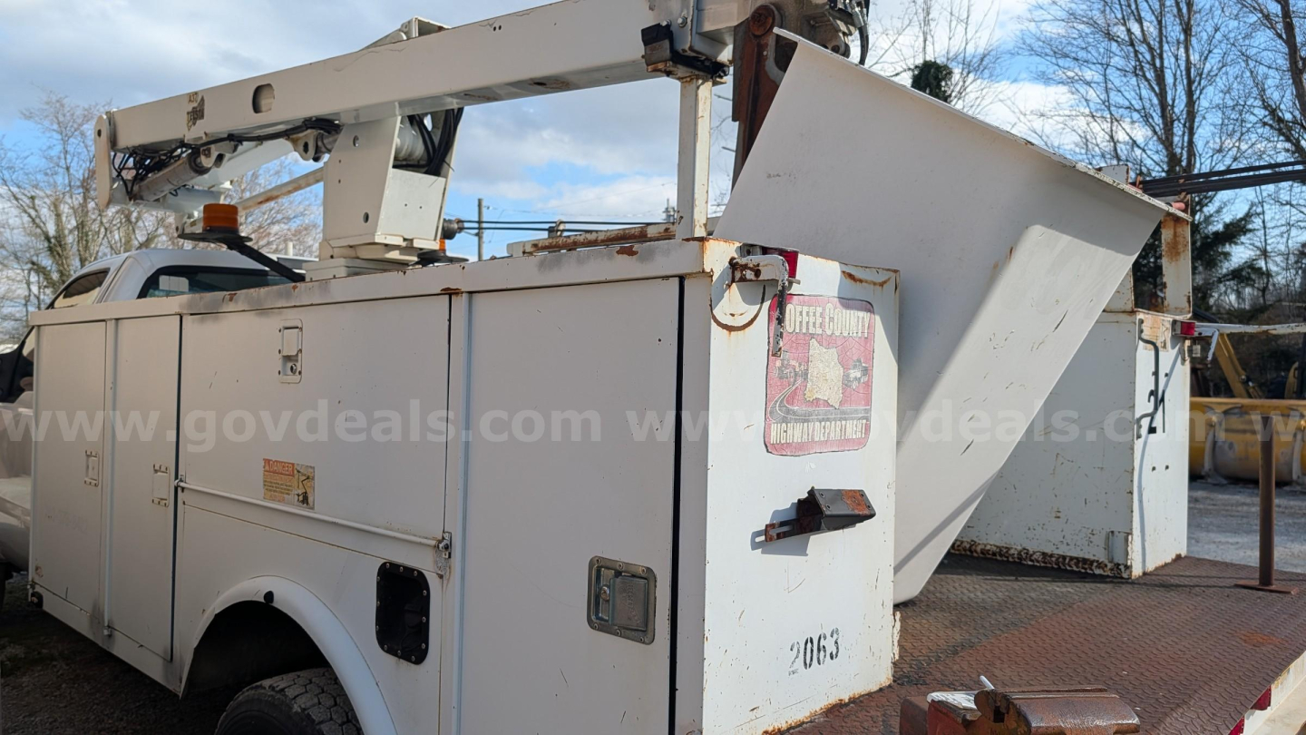Ford F-550 bucket truck body with boom lift in service bay, side compartments, and control panels visible.