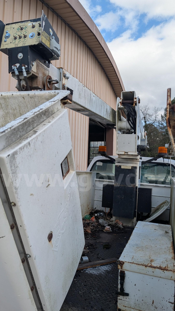 Equipment-only view of a bucket truck elevated platform with control box and hydraulic arm, showing metal framework and weathered white panels.