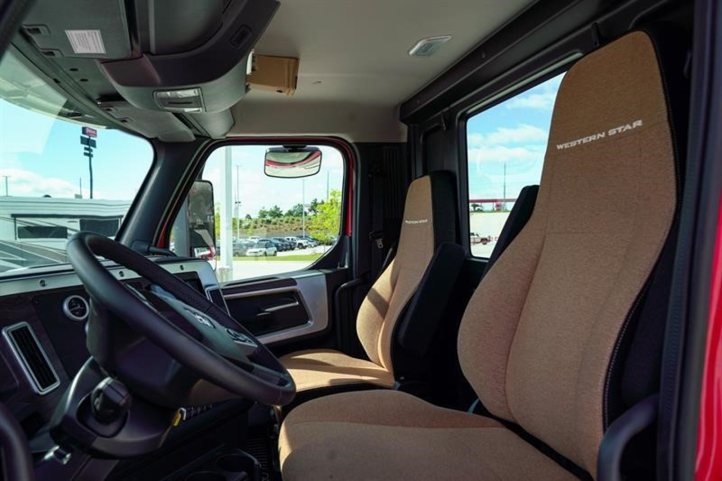 Western Star 49X truck interior showing driver seat and passenger seat with beige fabric, steering wheel, and dashboard view.
