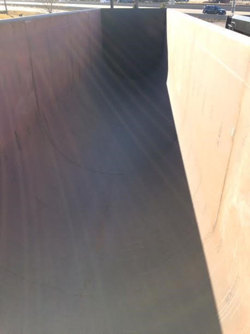 Dump trailer bed interior showing steel walls and a curved tail section