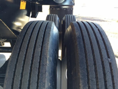 Trailer tires (dual axle) with black tread and rims visible; part of CPS Scrap Trailer undercarriage in outdoor setting.