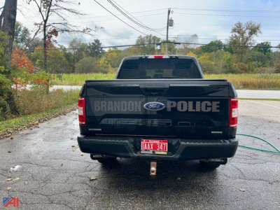 Ford police pickup truck rear view showing BRANDON POLICE on tailgate, Ford emblem, red license plate, hitch, and rear bumper.