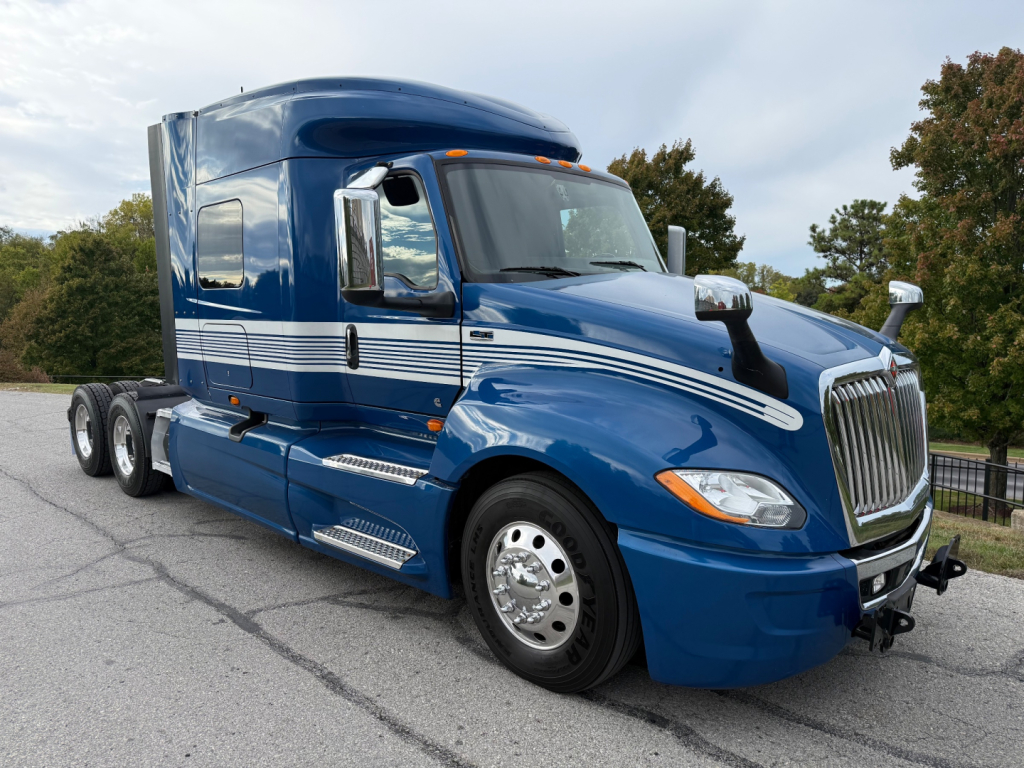 Blue International LT tractor-trailer cab in view with chrome mirrors and wheels, exterior decals, and sleeper cab, side view showing aerodynamic chrome intake and steps.