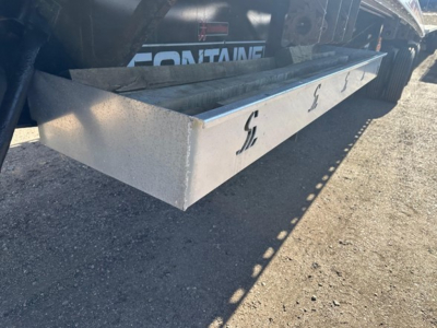 Flatbed trailer undercarriage showing a metal side rail with Fontaine branding and a silver aluminum step/bed extension.