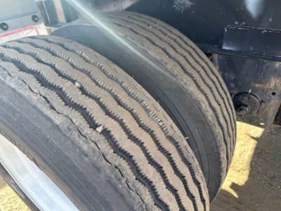 Front dual tires of a Fontaine Infinity trailer showing tread pattern and sidewall, with partial undercarriage visible.