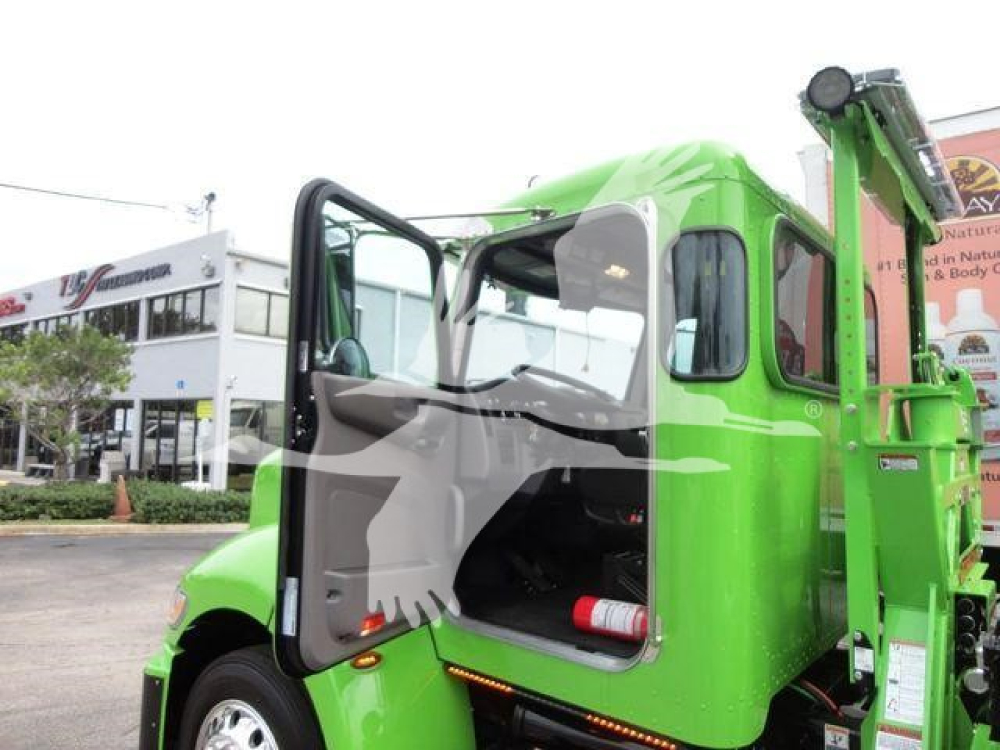 Truck cab opening with door ajar showing interior and green Peterbilt 337 rollback body.
