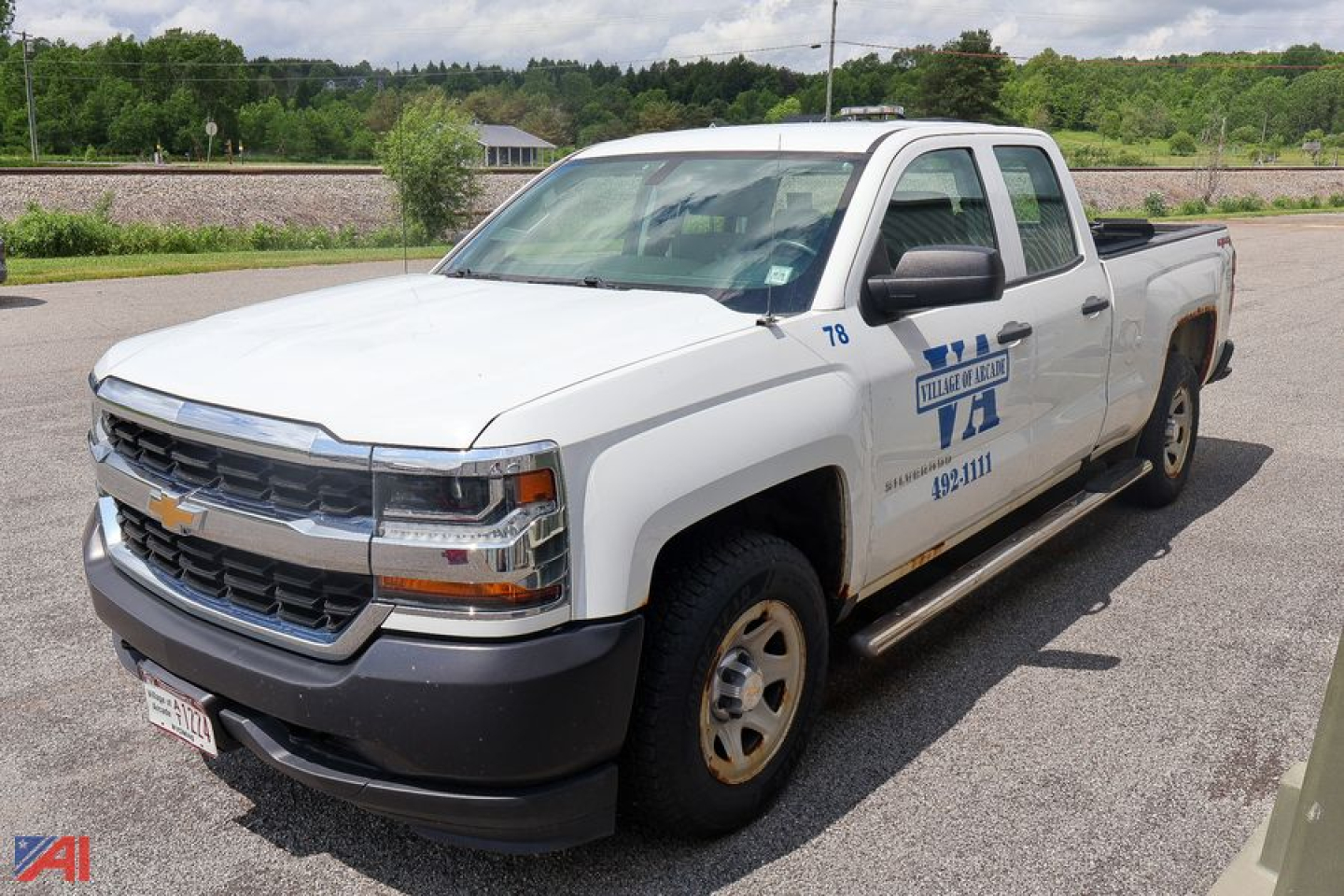 Chevrolet Silverado 1500 crew cab pickup truck in white with service graphics on the door, front grille and bumper visible.