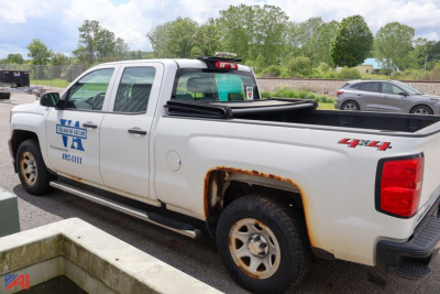 Chevrolet Silverado 1500 crew cab pickup truck in a parking lot, white, 4x4 badge on rear quarter panel, rust around wheel well, side steps visible.