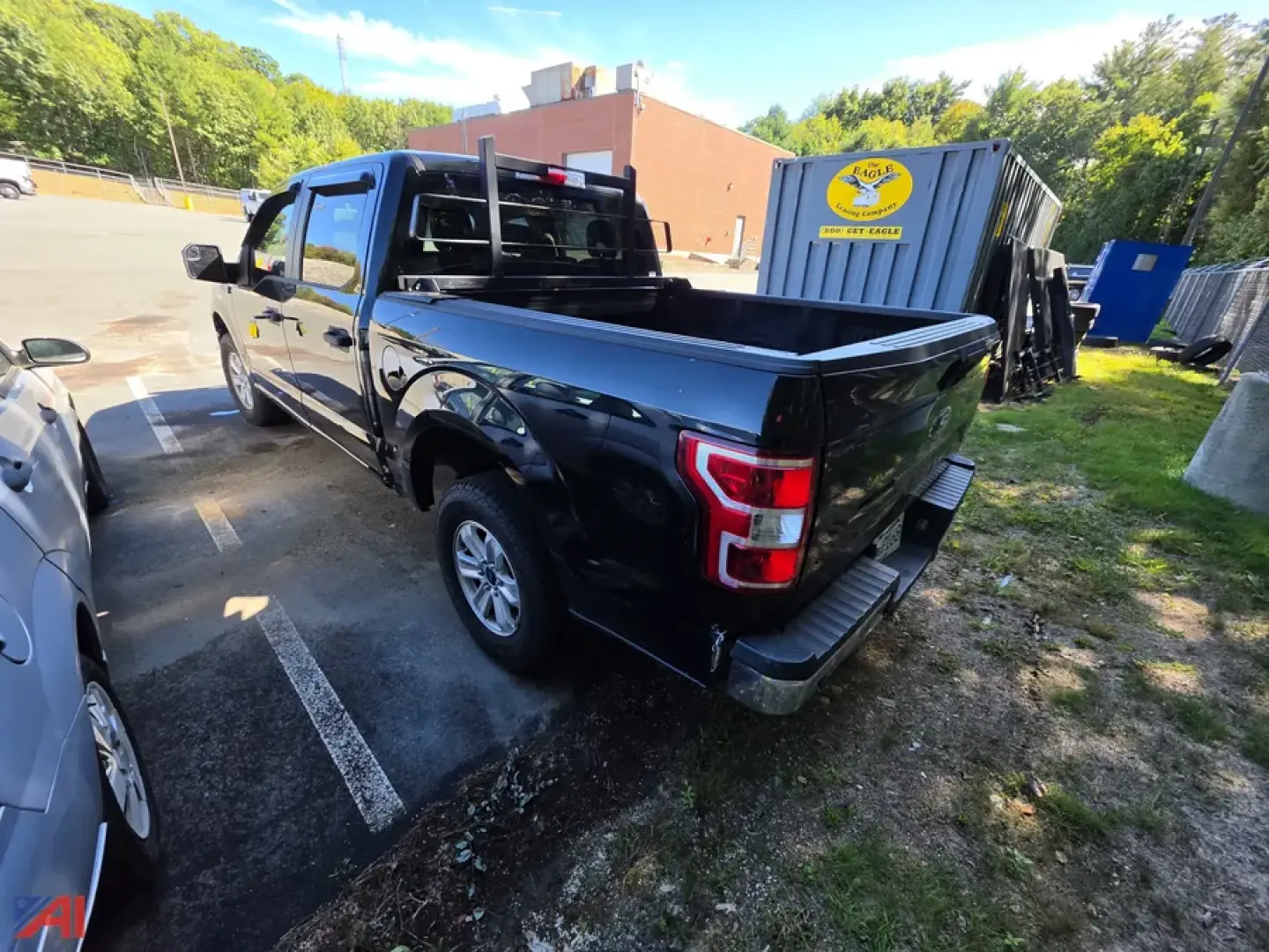 Truck bed view: 2018 Ford F-150 Crew Cab pickup with black paint, crew cab, 4x4; tailgate and rear bumper visible in a parking lot.
