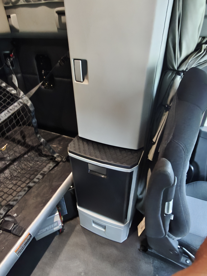 Kenworth T680 interior cabinet area with storage compartments and step, cabin seat visible.