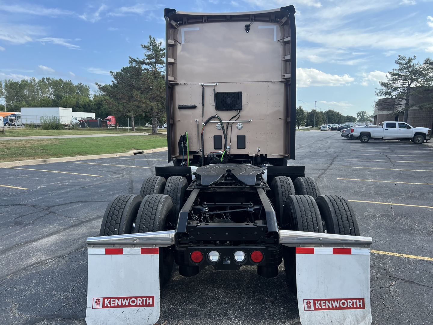 Kenworth T680 rear view showing chassis, dual rear axles, and fifth wheel under a sleeper cab; visibleKenworth logos on mud flaps.