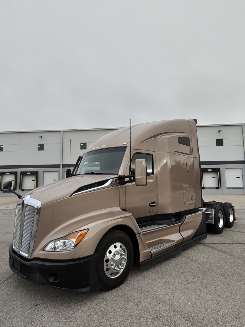 Kenworth T680 sleeper tractor truck in beige color, front-left view, with stock number 0630365 and VIN 1XKYDP9X4PJ243741 visible.