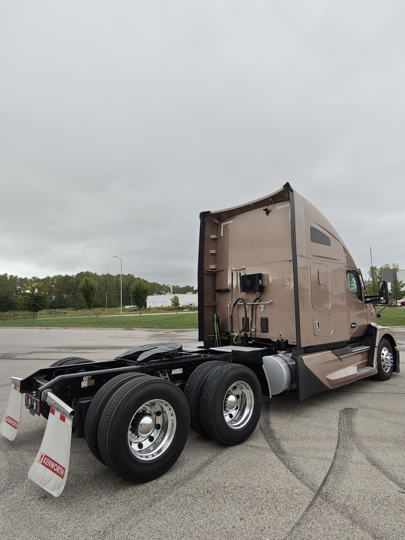 Kenworth T680 two-axle tractor with beige sleeper, rear view showing fifth-wheel area and dual rear tires. VIN tag and stock number not visible on cab.