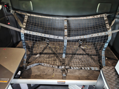 Trucks cab rear interior showing cargo net and flat floor with tie-downs in Kenworth T680 cargo area.