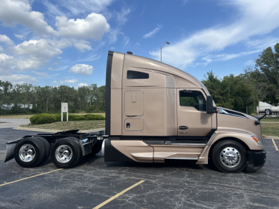 Kenworth T680 sleeper cab side view showing dual rear axles and tan paint.