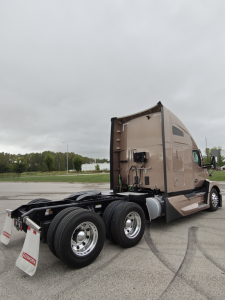 Kenworth T680 two-axle tractor with beige sleeper, rear view showing fifth-wheel area and dual rear tires. VIN tag and stock number not visible on cab.