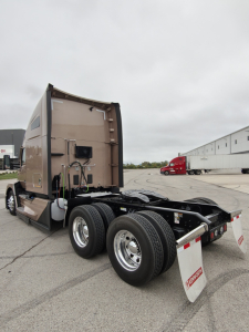 Kenworth T680 chassis cab rear view showing fifth wheel and dual rear axles with mud flaps and fuel lines in view.