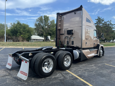 Kenworth T680 tractor rear view showing dual rear axles, tan cab, sleeper, and rear mud flaps.
