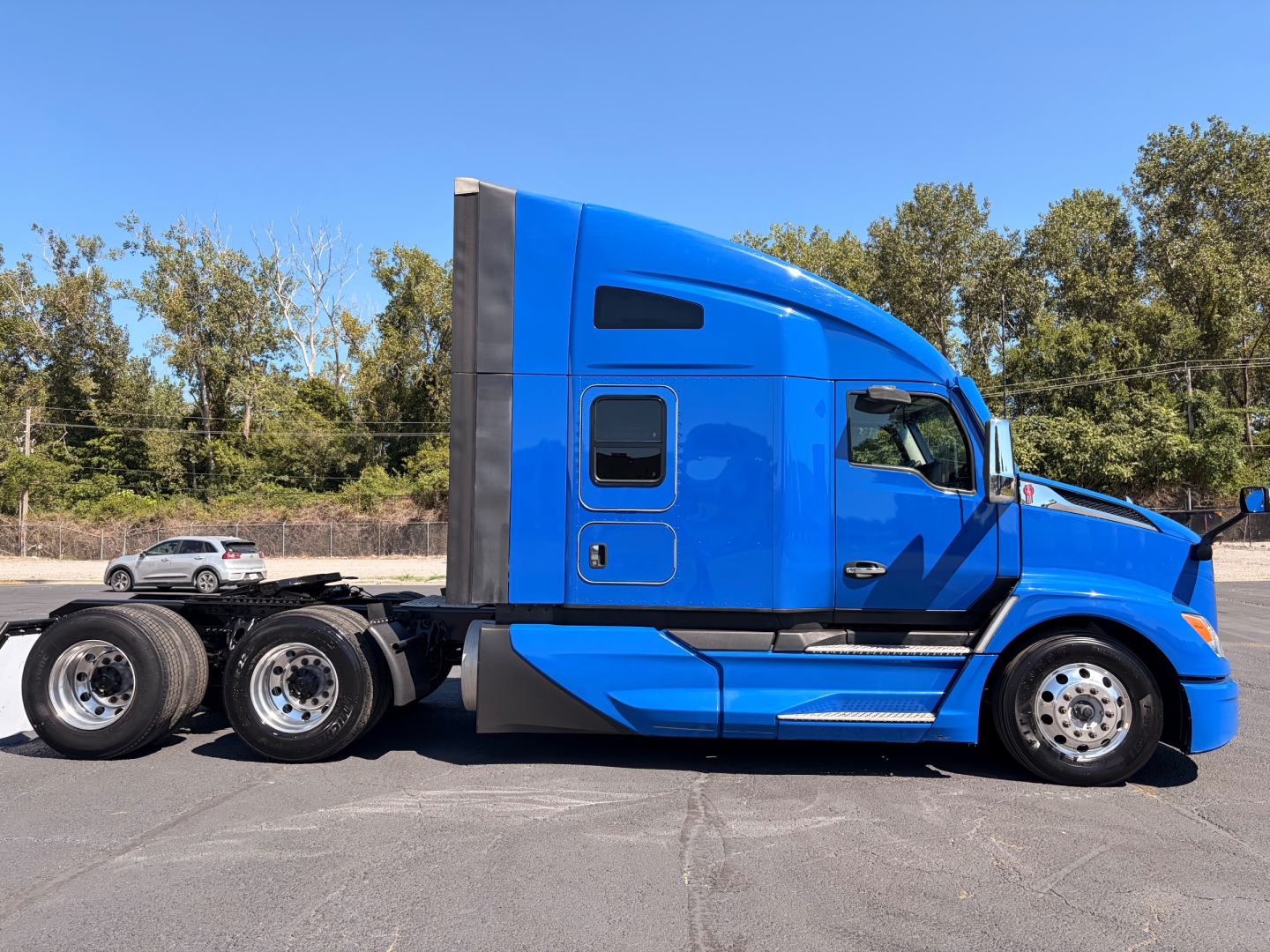 Kenworth T680 tractor in blue profile view showing sleeper cab and dual rear axles, side profile with windows and chrome wheels.