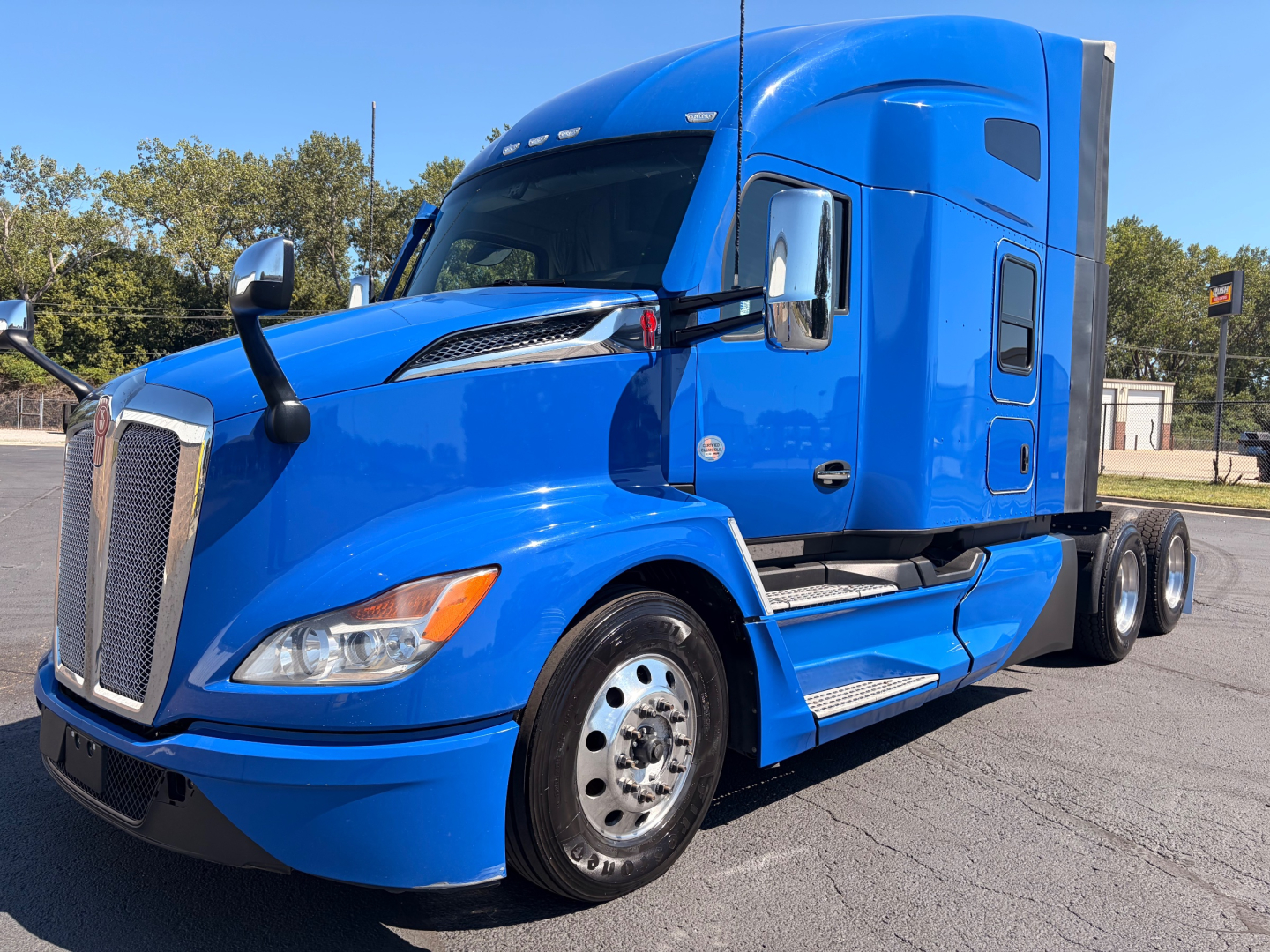 Blue Kenworth T680 tractor in profile view showing front grille, headlights, mirrors, and sleeper cab window.
