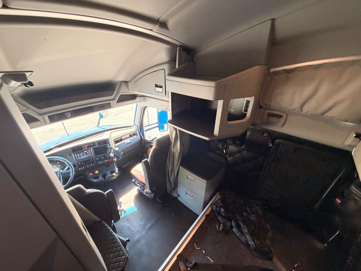Kenworth T680 cab interior showing sleeper bunk area with overhead shelf and storage compartments.
