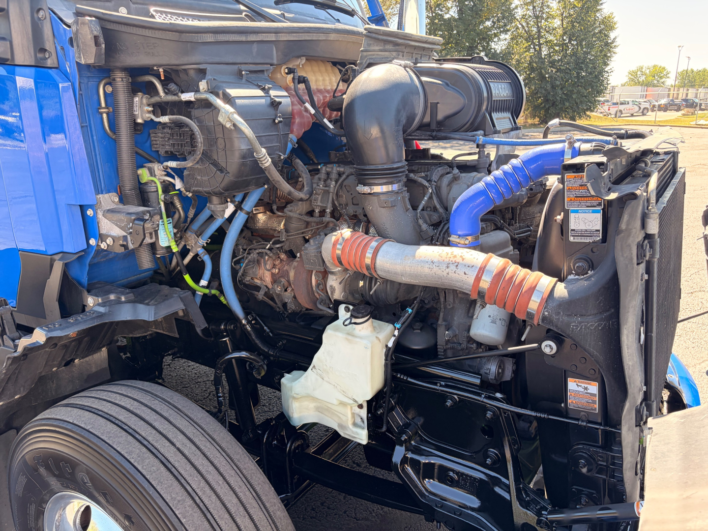 Kenworth T680 engine bay showing cooling system and intake hoses with blue silicone hose and radiator area.