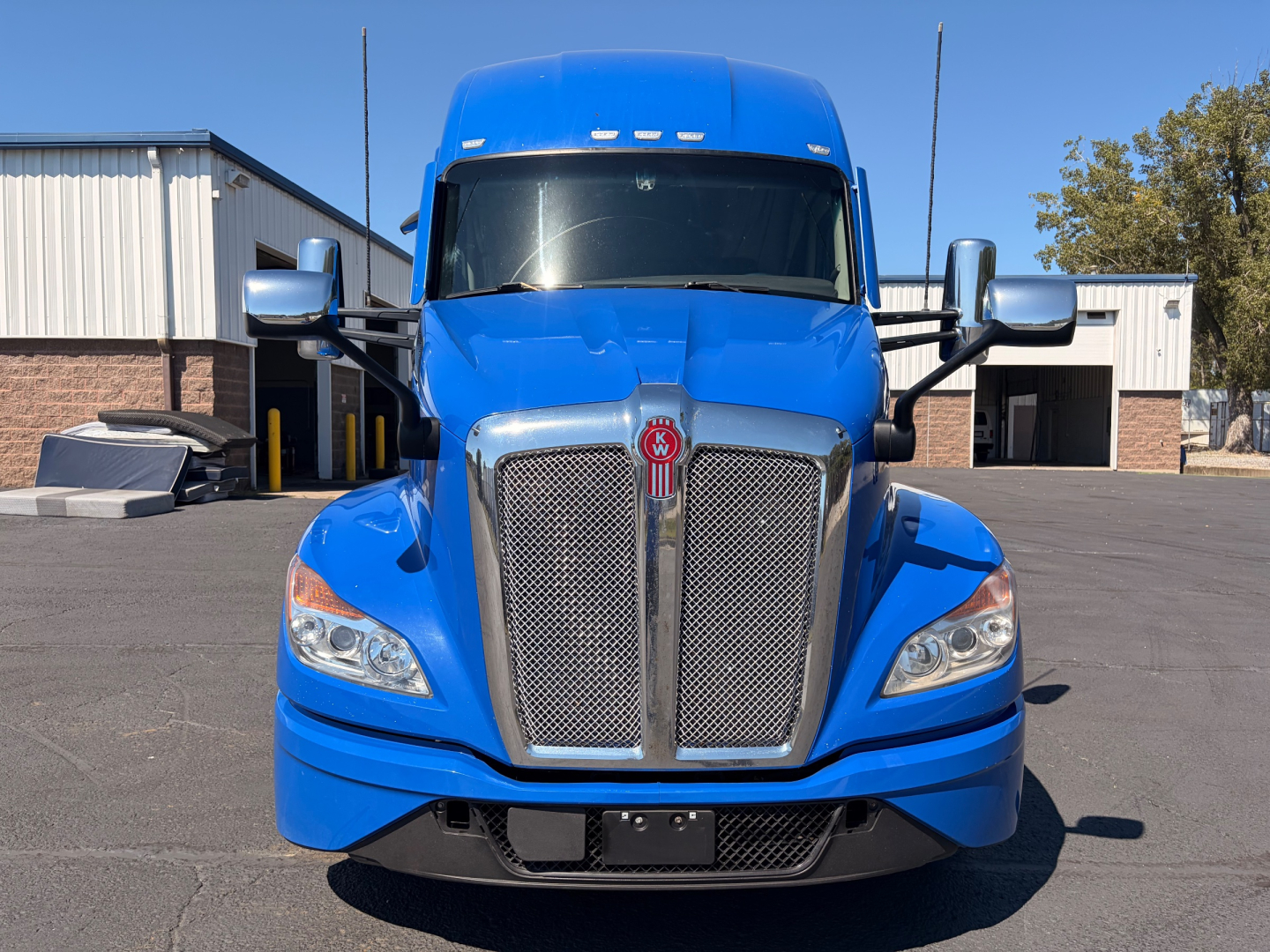 Kenworth T680 front view showing blue cab with large grille and emblem, headlights, mirrors
