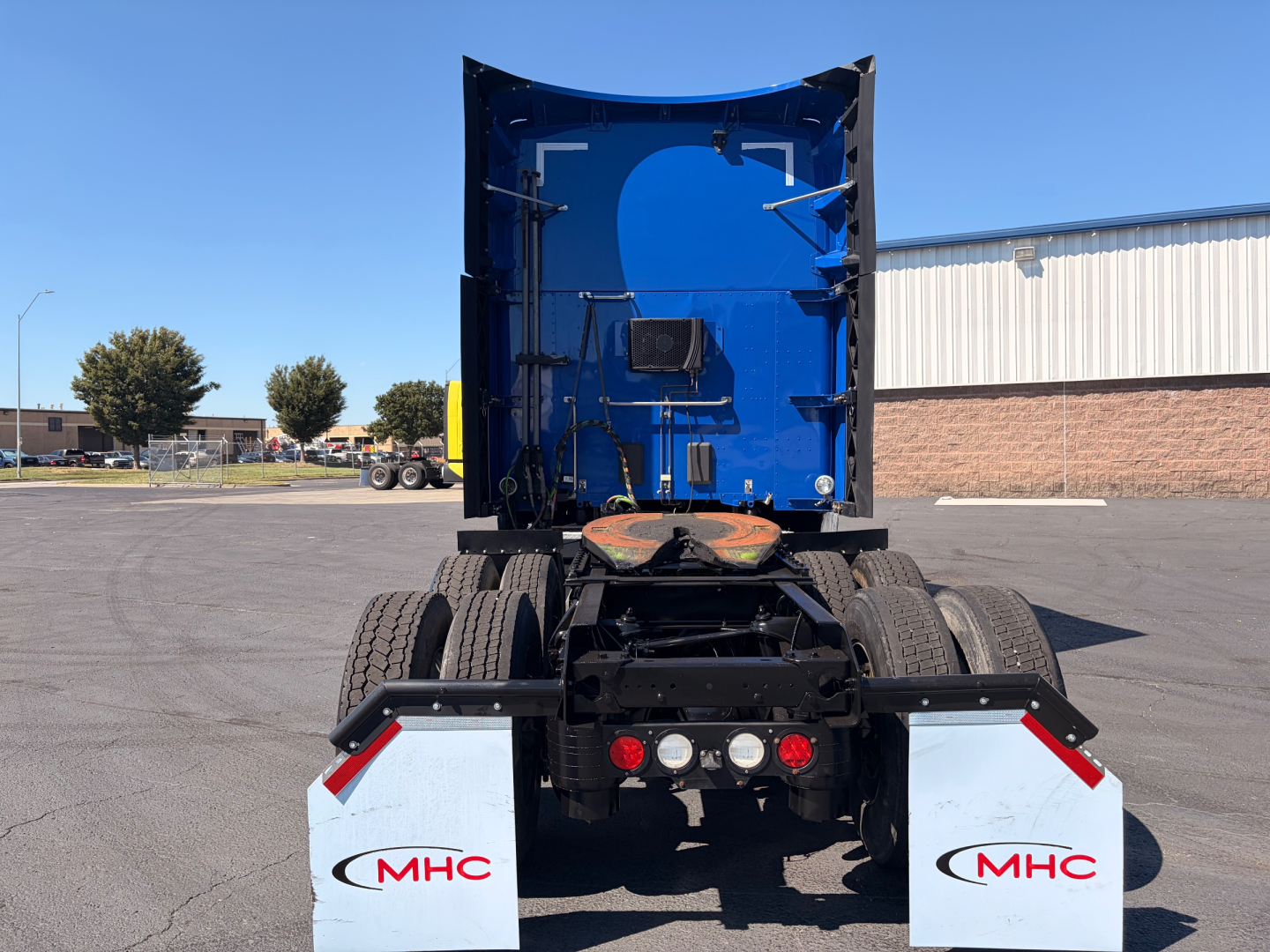 Kenworth T680 rear view showing chassis, fifth wheel, and mud flaps with MHC logos.