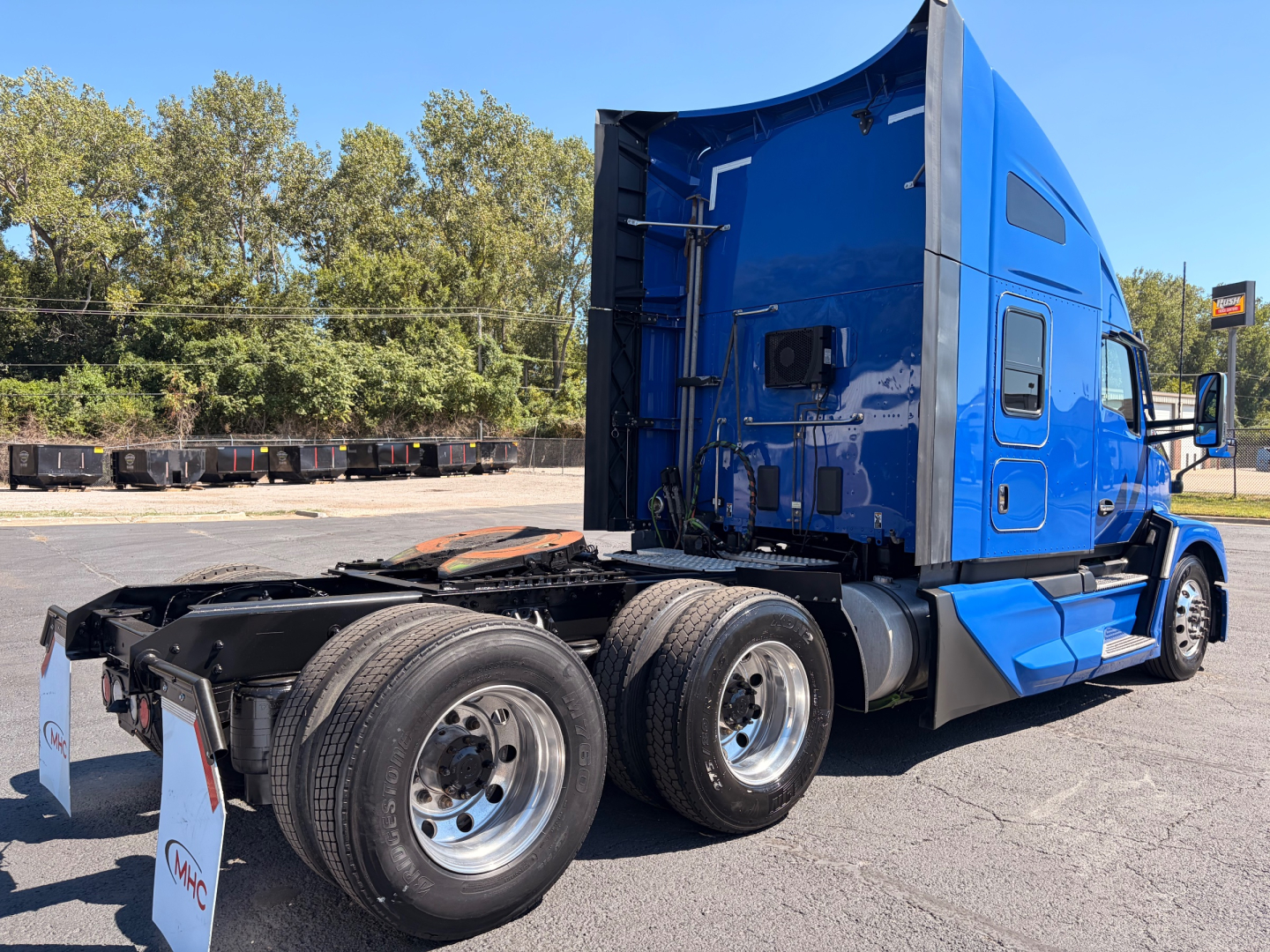 Kenworth T680 tractor in blue cab, three-quarter rear view showing sleeper, dual rear axles, and fifth wheel area; no visible text on components.