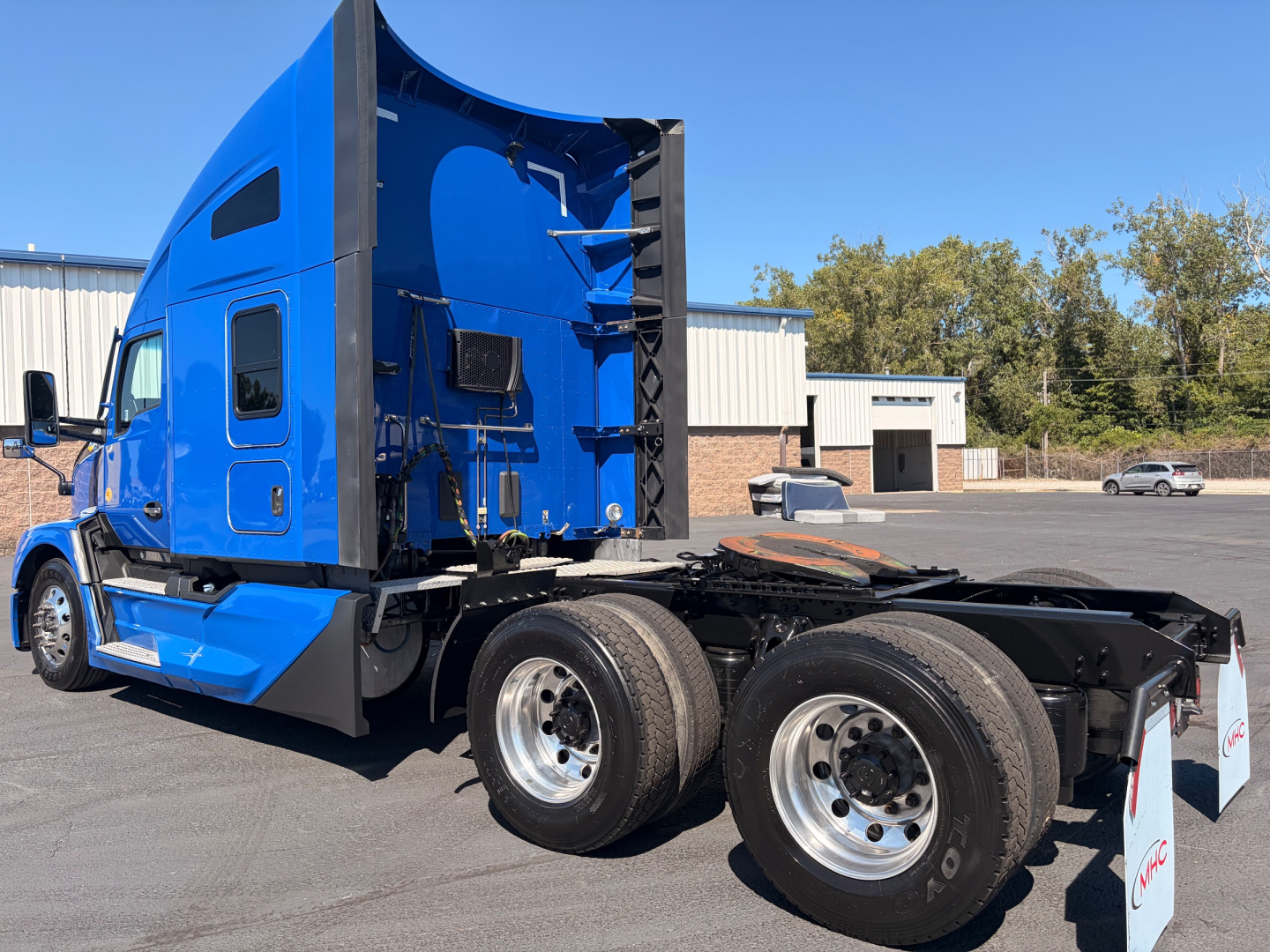 Kenworth T680 truck tractor side and rear view showing dual rear axles, blue sleeper cab, and chassis with mounting for fifth wheel.