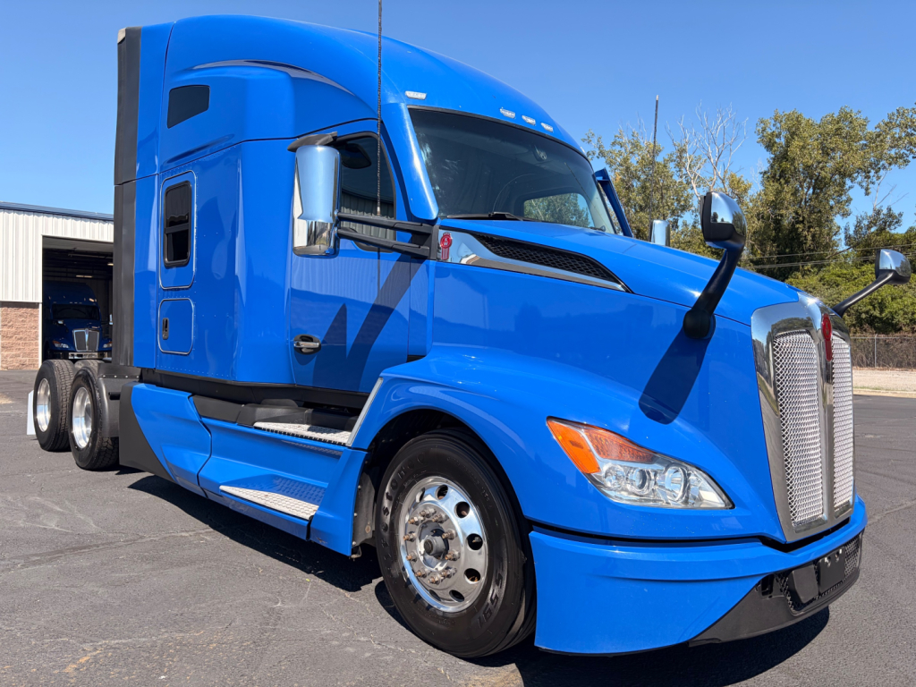 Kenworth T680 blue cab-over-trailer tractor, front-right view, showing grille, headlights, and side mirrors.