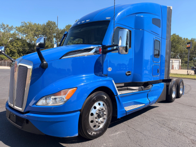 Blue Kenworth T680 tractor in profile view showing front grille, headlights, mirrors, and sleeper cab window.
