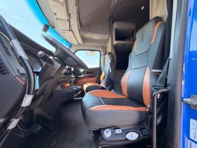 Kenworth T680 cabin interior showing driver seat with black and orange upholstery, dashboard, and entry door.
