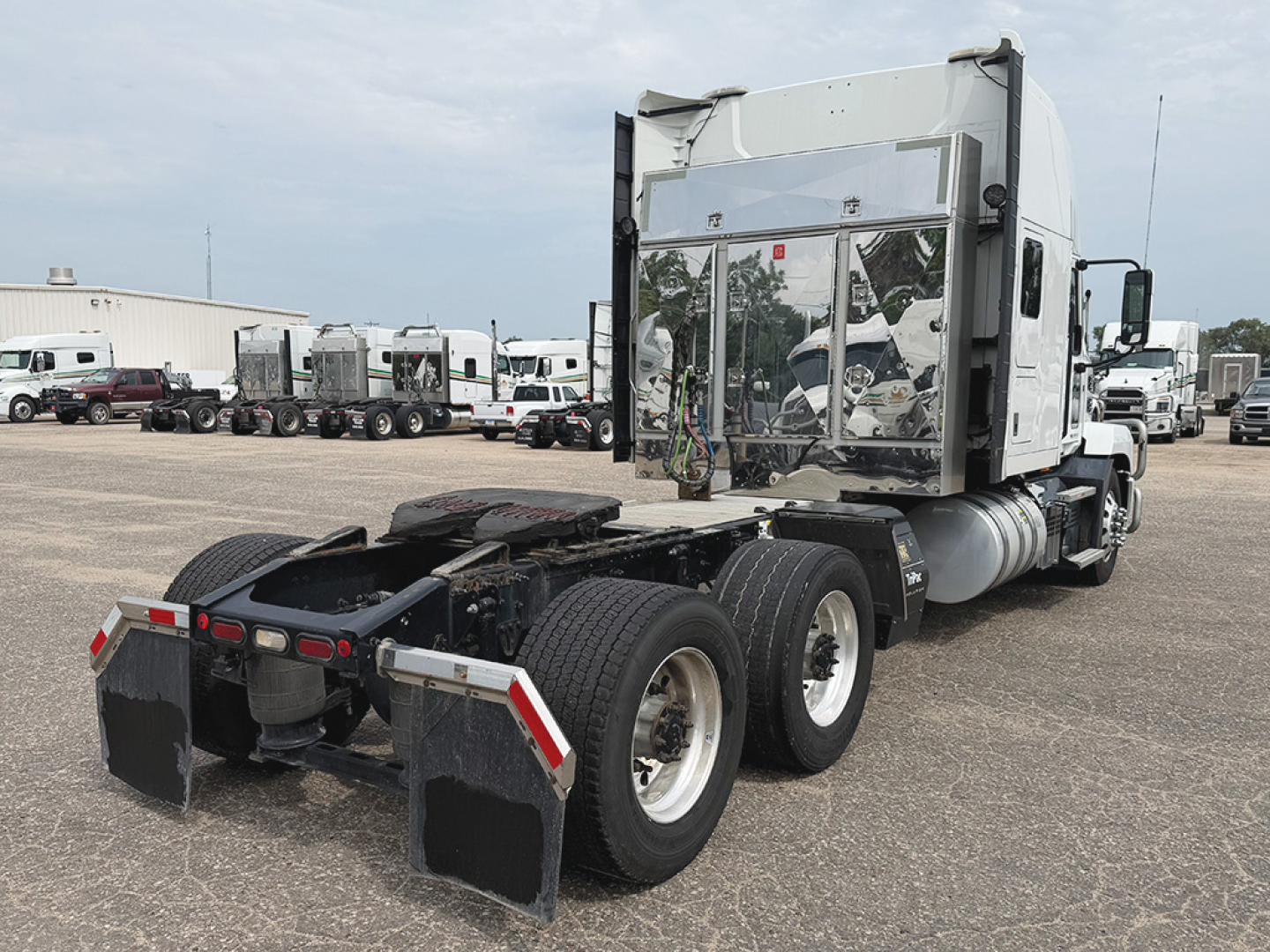 Truck chassis of a Mack Anthem tractor showing rear dual axles and fifth wheel, with sleeper cab in background.