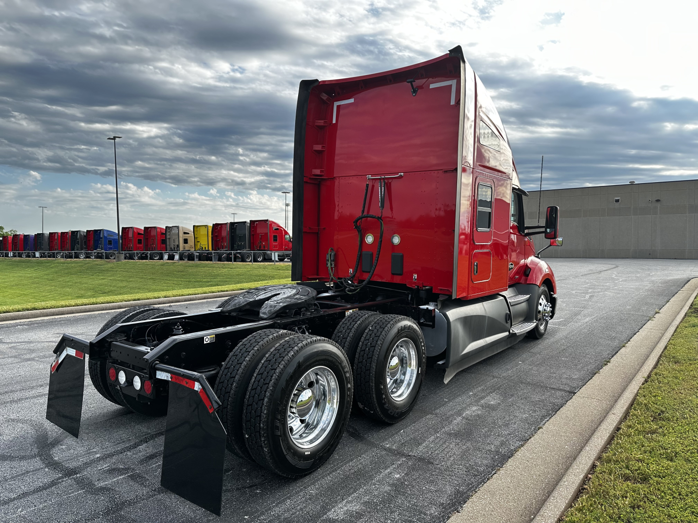 Kenworth T680 tractor from rear-left side showing triple rear axles and red sleeper cab.