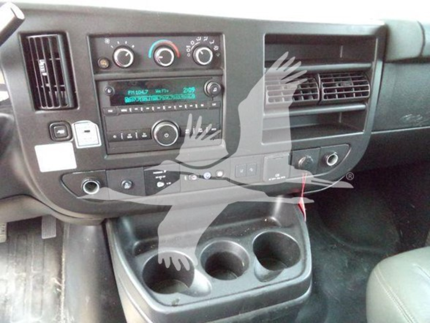 Dashboard area of a 2021 GMC G3500 cargo van showing center console with radio and climate controls, cup holders, and storage pockets.